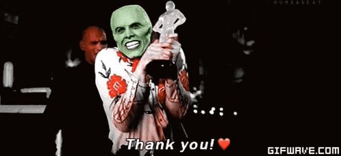 A Man With A Green Mask Is Holding A Trophy And Saying Thank You . GIF