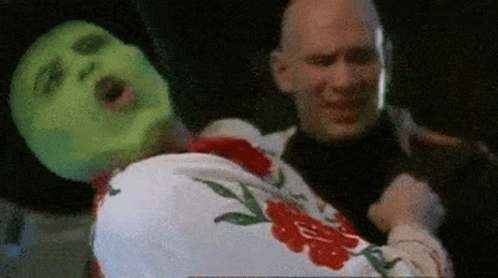 A Man With A Green Mask Is Holding A Woman GIF