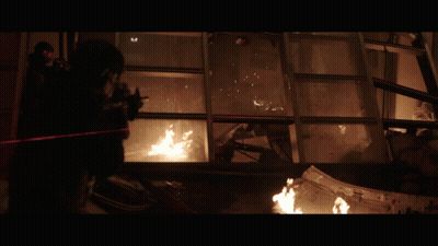 A Man With A Gun Is Standing In Front Of A Window With A Fire Coming Out Of It GIF