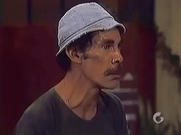 A Man With A Hat On His Head And A Mustache Is Looking At The Camera . GIF
