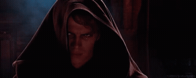 A Man With A Hood On His Head Is Looking At The Camera With A Serious Look On His Face . GIF