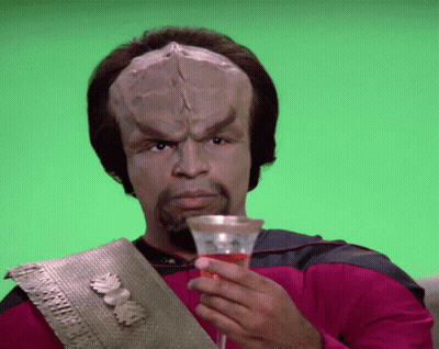 A Man With A Huge Head Is Holding A Glass Of Wine GIF