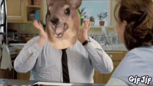 A Man With A Kangaroo Mask On His Face Is Talking To A Woman In A Kitchen . GIF