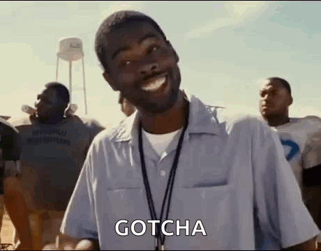 A Man With A Lanyard Around His Neck Is Smiling While Standing In Front Of A Group Of People . GIF
