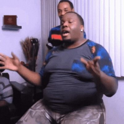 A Man With A Large Belly Is Sitting In Front Of A Window With His Hands Outstretched GIF
