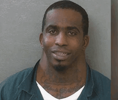 A Man With A Large Neck And A Tattoo On His Neck Is Smiling . GIF