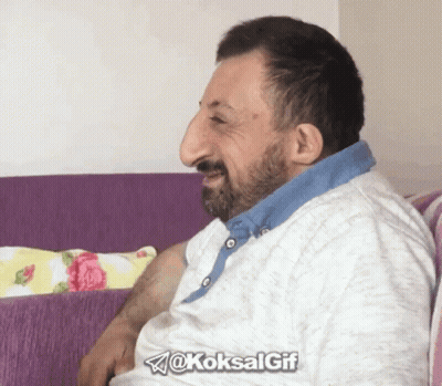 A Man With A Large Nose Is Sitting On A Purple Couch With The Hashtag @Koksalgif