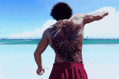 A Man With A Large Tattoo On His Back Is Standing On A Beach GIF
