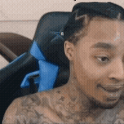 A Man With A Lot Of Tattoos Is Sitting In A Chair . GIF
