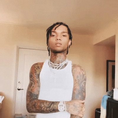 A Man With A Lot Of Tattoos Is Wearing A White Tank Top With His Arms Crossed GIF