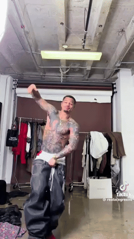 a man with a lot of tattoos on his body is dancing in a room .