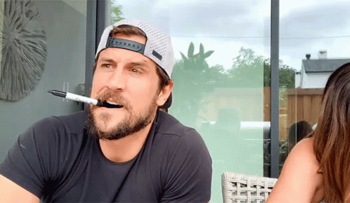 A Man With A Marker In His Mouth And A Hat On GIF