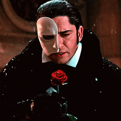 A Man With A Mask On His Face Is Holding A Rose . GIF