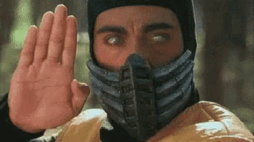 A Man With A Mask On His Face Is Making A Stop Sign With His Hand . GIF