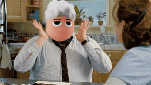 A Man With A Mask On His Face Is Talking To A Woman In A Kitchen GIF