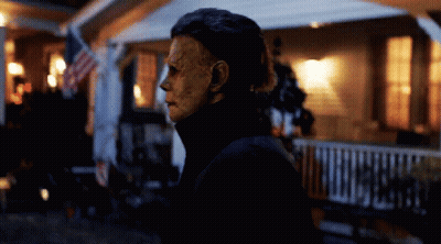 A Man With A Mask On His Face Stands In Front Of A House GIF