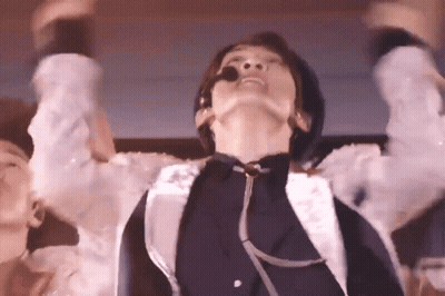 A Man With A Microphone In His Mouth Is Dancing On A Stage . GIF