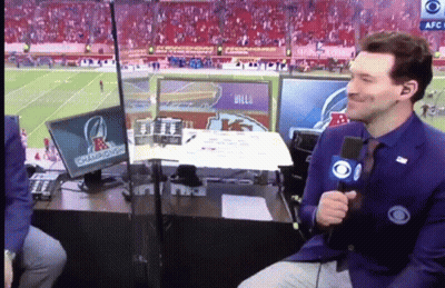 A Man With A Microphone Sitting In Front Of A Screen That Says Champions On It GIF