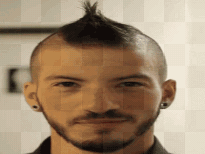 A Man With A Mohawk And A Beard Is Smiling . GIF