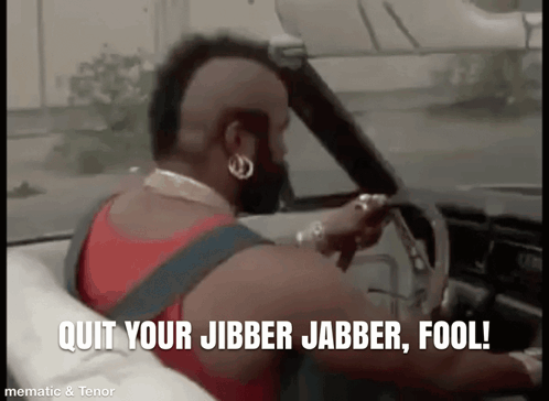 A Man With A Mohawk Is Driving A Car With The Words `` Quit Your Jibber Jabber Fool '' Written On The Screen . GIF
