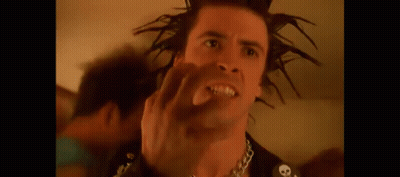 A Man With A Mohawk Is Making A Funny Face While Wearing A Chain Around His Neck . GIF