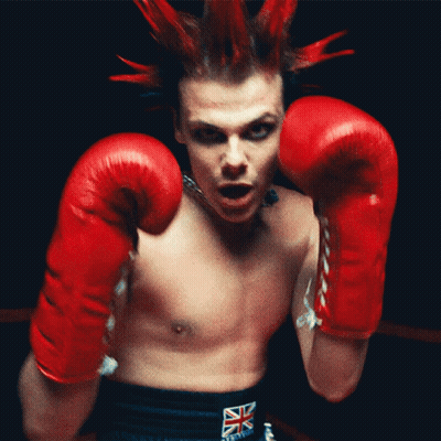 A Man With A Mohawk Wearing Red Boxing Gloves And A British Flag Belt GIF