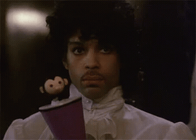 A Man With A Monkey On His Head Is Holding A Cup . GIF