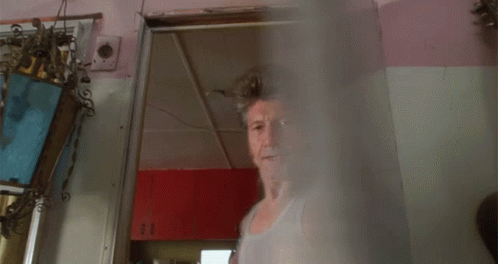 A Man With A Mullet And A Tank Top Stands Next To A Woman GIF