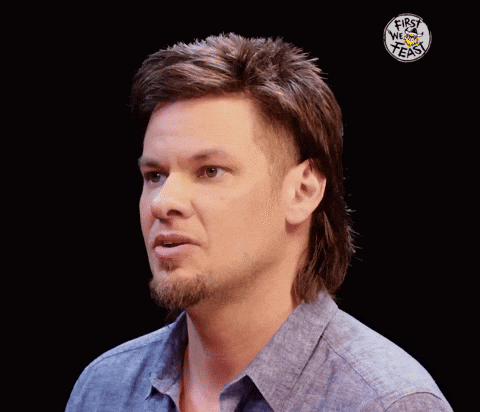 A Man With A Mullet Has The Words First We Feast On His Shirt GIF