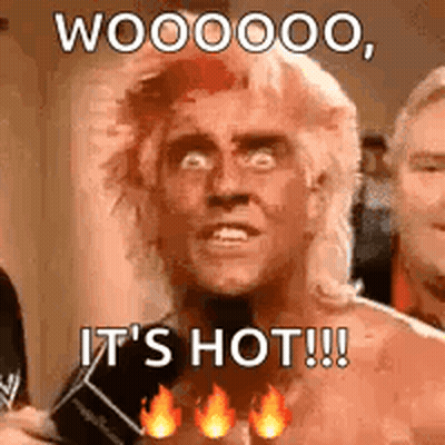 A Man With A Mullet Is Holding A Microphone And Says `` It 'S Hot ! '' GIF