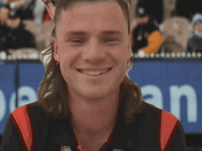 A Man With A Mullet Is Smiling In Front Of A Sign That Says Open GIF