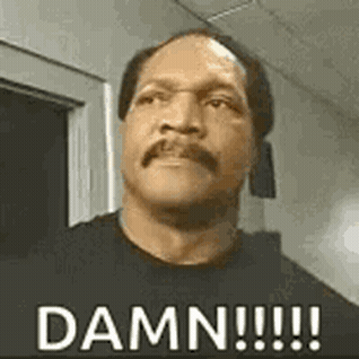 A Man With A Mustache And A Black Shirt Is Standing In Front Of A Door And Says `` Damn !!! '' . GIF