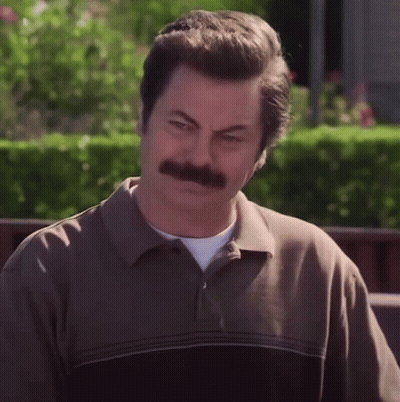 A Man With A Mustache And A Brown Shirt Looks At The Camera GIF
