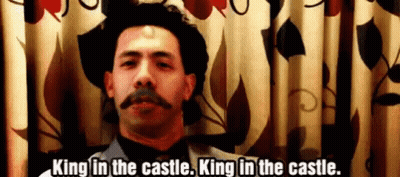 A Man With A Mustache And A Hat Is Standing In Front Of A Curtain And Says King In The Castle . GIF