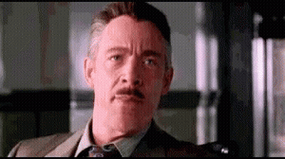 A Man With A Mustache And A Suit And Tie Is Making A Funny Face . GIF