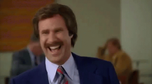 A Man With A Mustache And A Suit Is Laughing . GIF