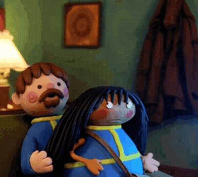 A Man With A Mustache And A Woman With Long Black Hair Are Sitting On A Couch GIF