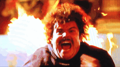 A Man With A Mustache And Curly Hair Is Screaming In Front Of A Fire GIF