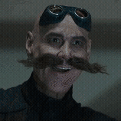 A Man With A Mustache And Goggles On His Head Is Eating Something GIF
