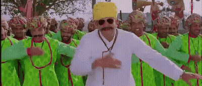 A Man With A Mustache And Sunglasses Is Dancing In Front Of A Crowd Of Men Wearing Green Clothes And Hats . GIF