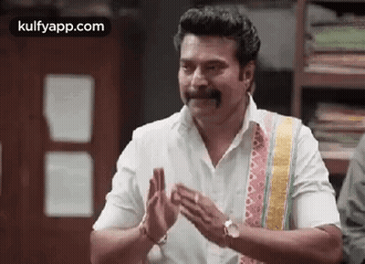 A Man With A Mustache Is Clapping His Hands While Wearing A White Shirt . GIF