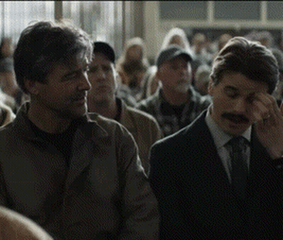 A Man With A Mustache Is Covering His Eyes In A Crowd GIF