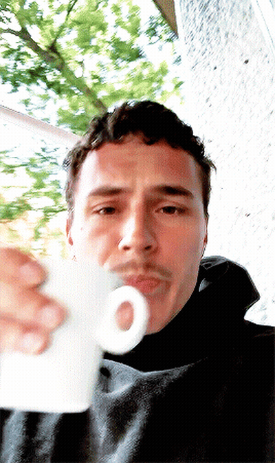 A Man With A Mustache Is Drinking From A White Cup With An O On It GIF