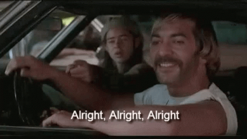 A Man With A Mustache Is Driving A Car With Another Man Sitting In The Back Seat . GIF