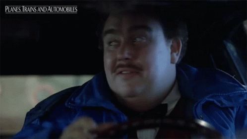 A Man With A Mustache Is Driving A Car With Planes Trains And Automobiles Written Above Him GIF