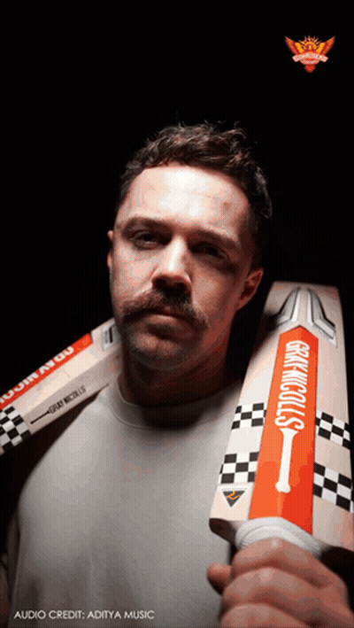 A Man With A Mustache Is Holding A Cricket Bat That Says Gray Nicolls GIF