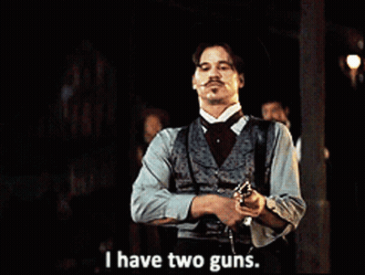 A Man With A Mustache Is Holding A Gun And Says I Have Two Guns GIF