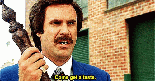 A Man With A Mustache Is Holding A Wooden Pole And Says Come Get A Taste GIF