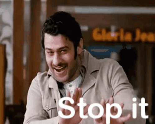 A Man With A Mustache Is Laughing And Saying `` Stop It '' With His Hands . GIF