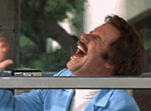 A Man With A Mustache Is Laughing While Looking Out Of A Car Window . GIF